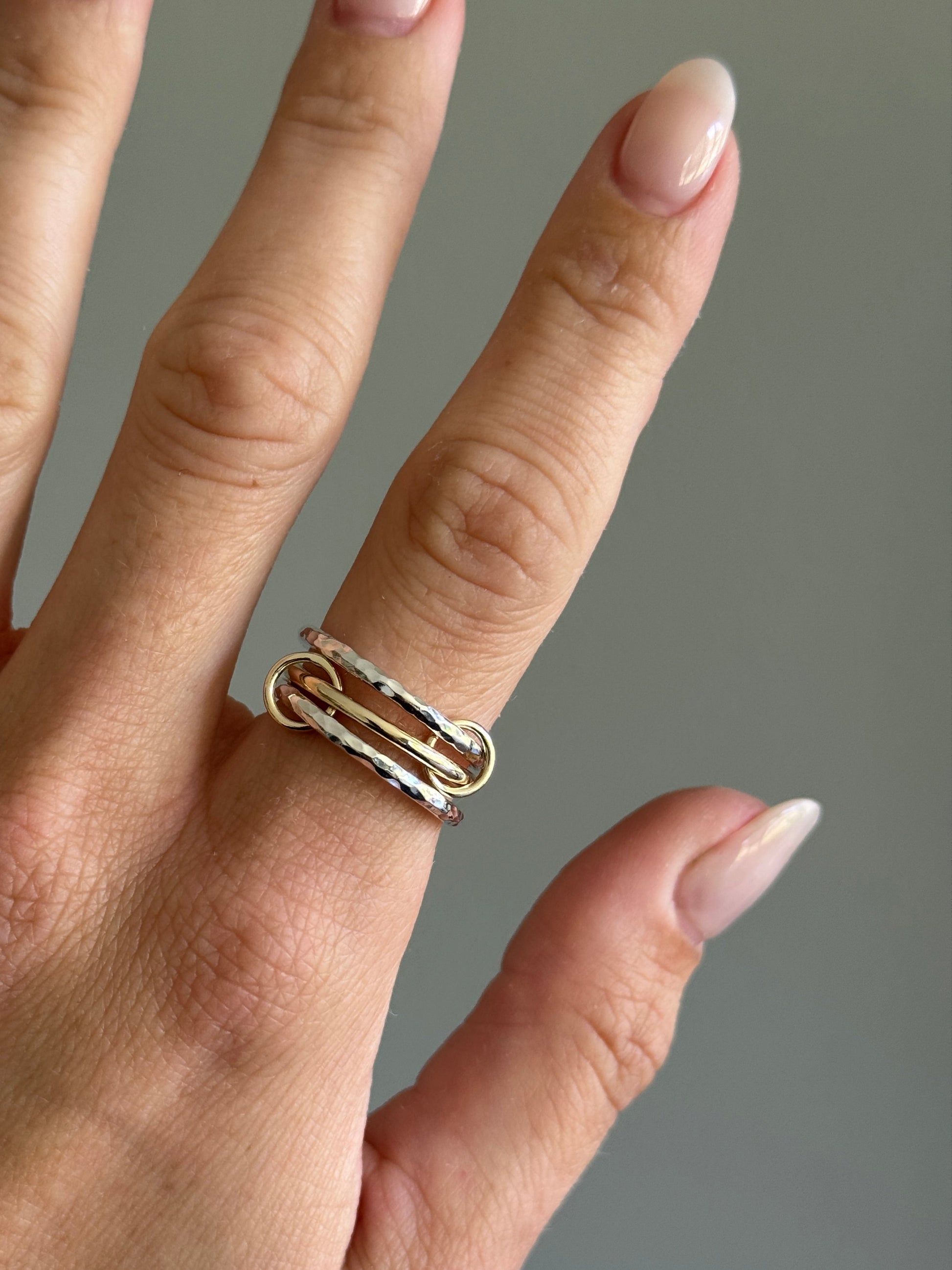 Hand wearing a gold ring on a neutral background